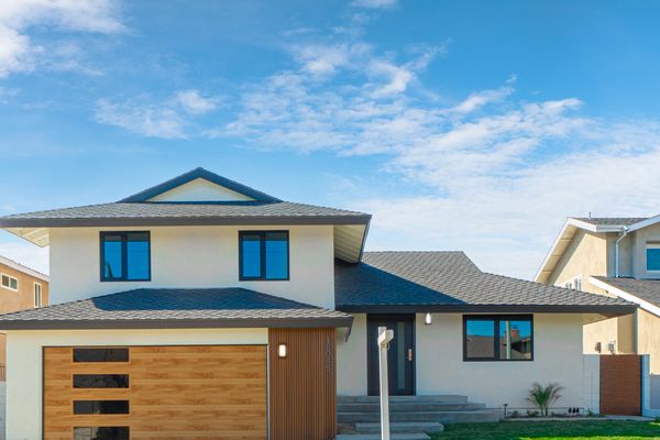 Modern two-story house with wooden garage door and green lawn.