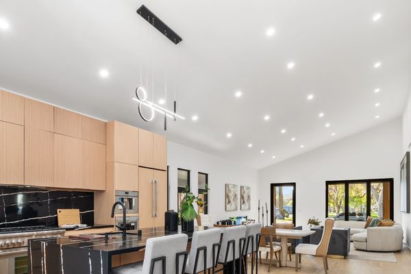Modern open-concept kitchen and living area with light wood floors and black marble accents.