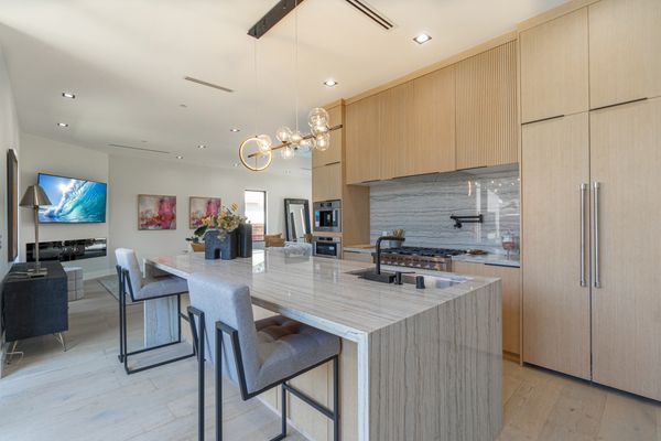 Modern kitchen with marble island and beige wood cabinetry.