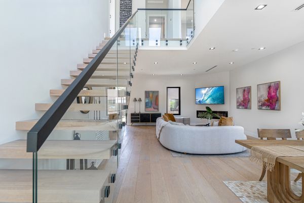 Modern living room with glass staircase and cozy seating area.