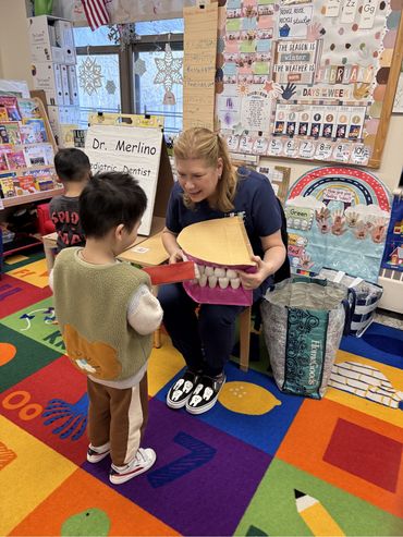 Dr. Merlino instructing children on proper dental hygiene at school visit