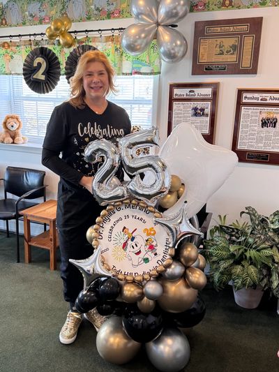 Dr. Merlino standing with celebratory 25th anniversary balloon display