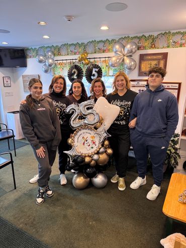 Dr. Merlino and patients smiling with celebratory 25th anniversary balloons