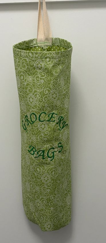 Green grocery bag holder hanging on a wall.