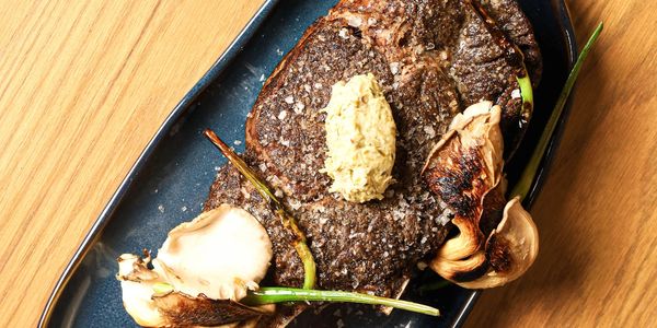 Grilled steak with garlic and herbs on a black plate.