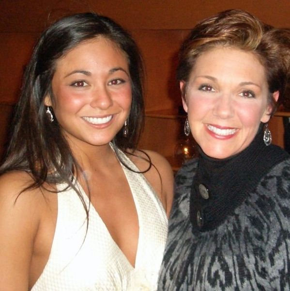 Two smiling women posing together indoors.