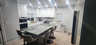 Modern kitchen with marble island and white cabinets.