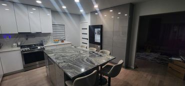 Modern kitchen with marble island, stainless steel oven, and smart refrigerator.