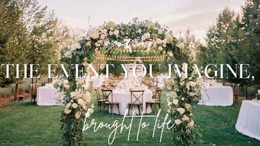Elegant outdoor wedding setup with floral arch and dining tables.