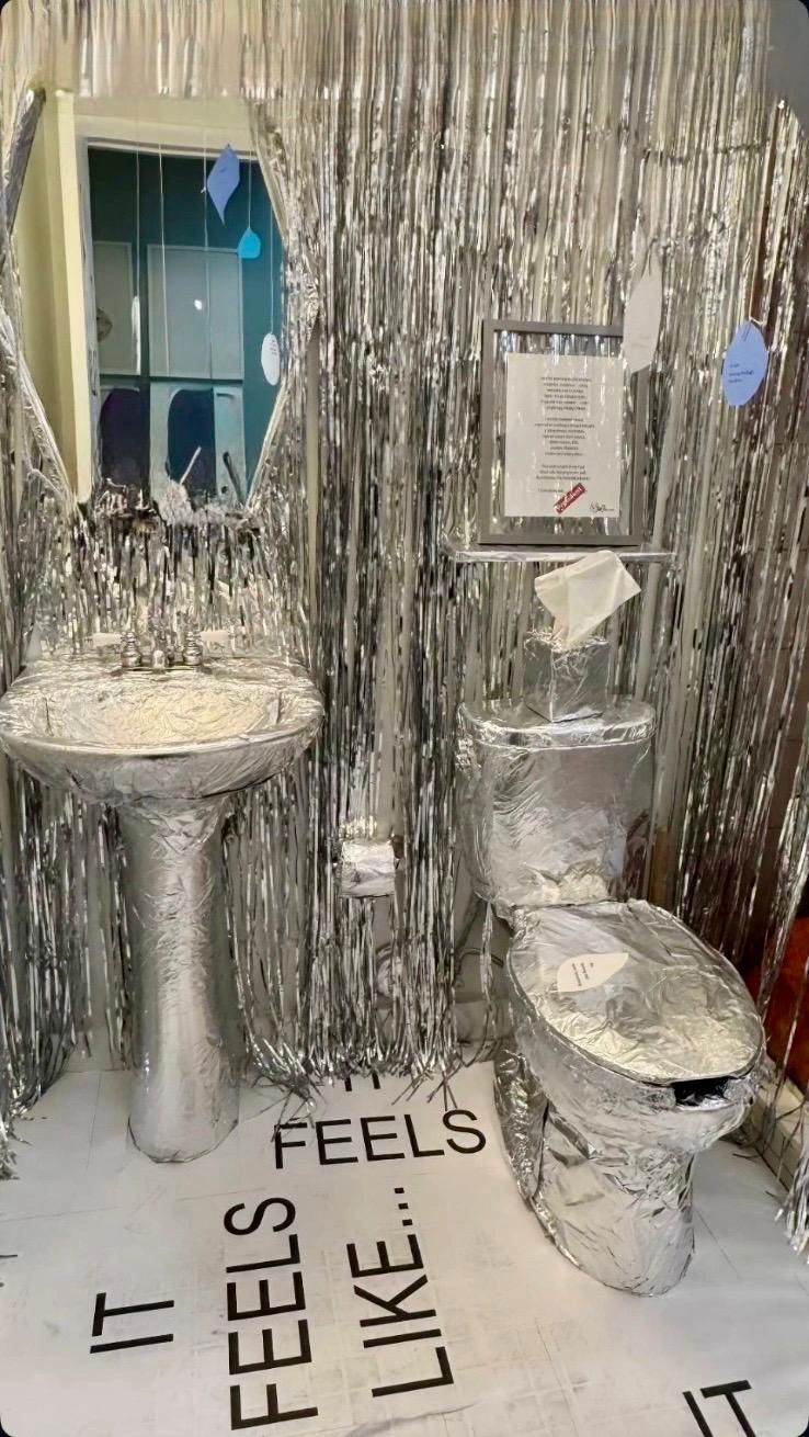 Bathroom wrapped in shiny silver foil with text on the floor.