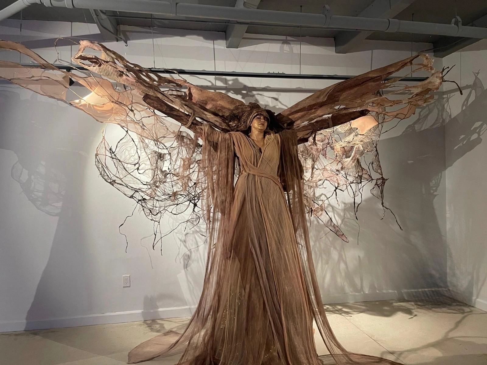 Artistic sculpture of a woman with large, intricate, wing-like extensions.