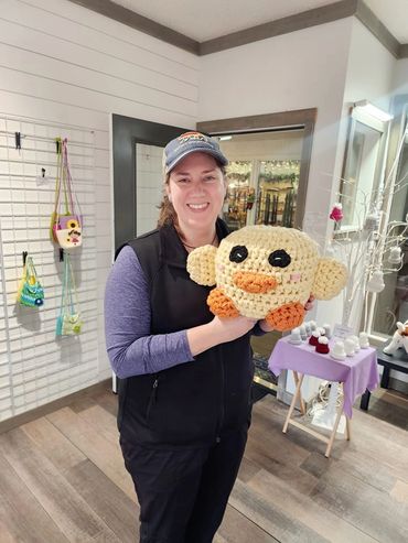Woman smiling and holding a crocheted plush toy.
