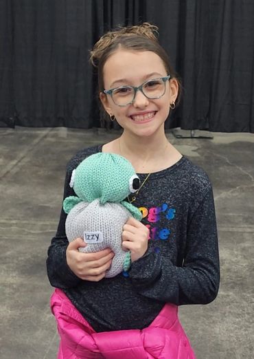Smiling girl holding a knitted toy.