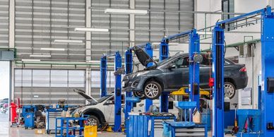 Modern car repair workshop with vehicles on lifts and open hoods.