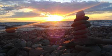 Stacked stones on a rocky beach during sunset.
