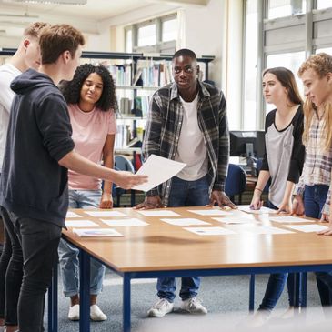A group of young people collaborating around a table in a library.