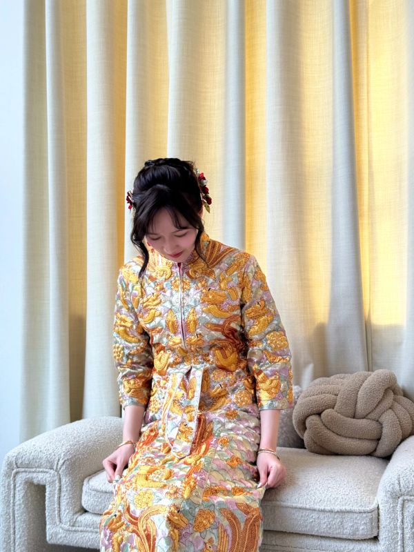 Woman in ornate traditional dress sitting on a sofa.