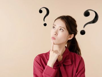 Woman thinking with question marks around her head.