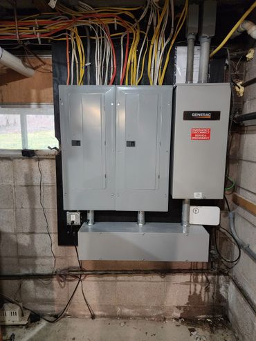 Electrical panel and disconnect box mounted on a basement wall with organized wiring.
