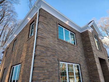 Two-story brick house with white trim and large windows under a clear blue sky.