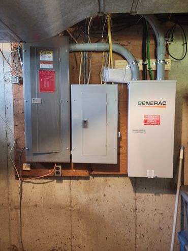 Electrical panels and a Generac emergency disconnect unit mounted on a basement wall.