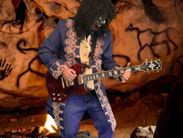 Person in ornate coat and mask playing electric guitar inside a cave with ancient wall art.