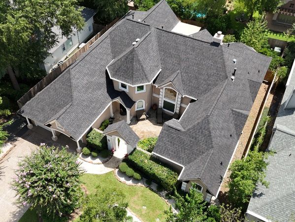 Aerial view of a large suburban house with a dark roof and landscaped garden.