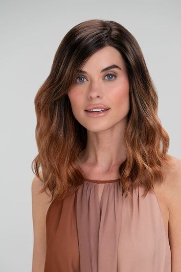 Woman with wavy ombre hair and neutral makeup in a sleeveless top.