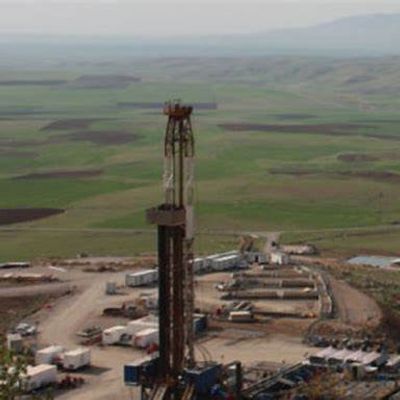 Oil drilling rig set in a vast green landscape.