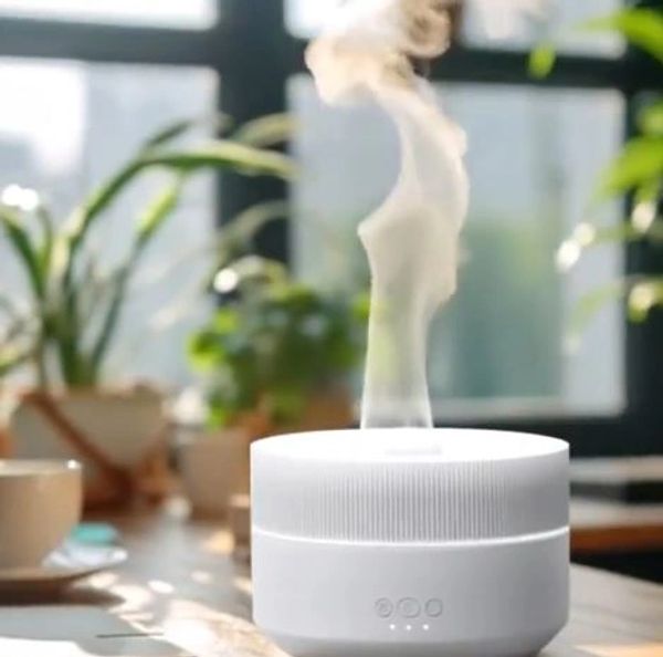 A white essential oil diffuser releasing mist in a cozy room with plants.