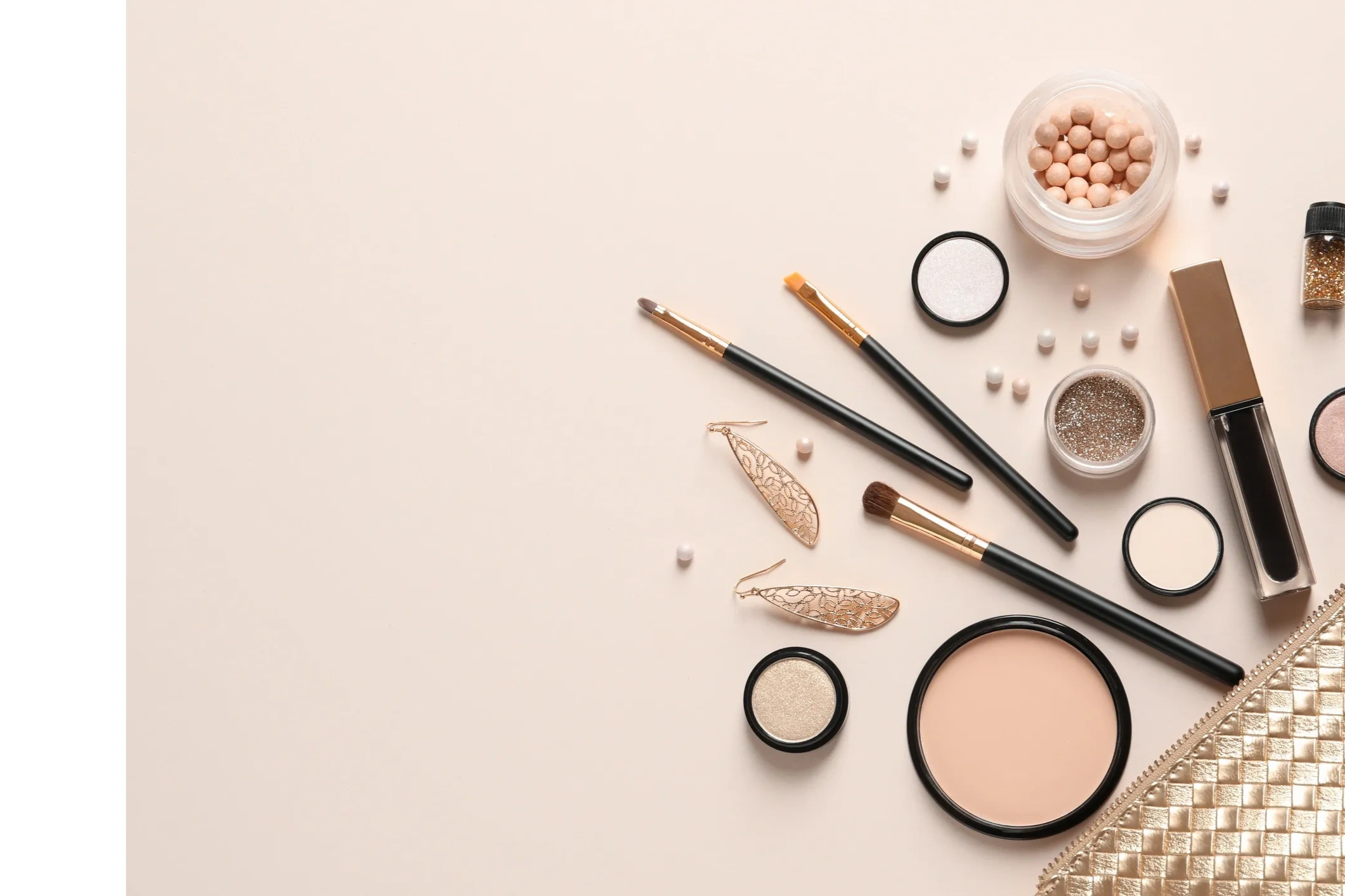 Elegant makeup products and brushes arranged on a beige background.