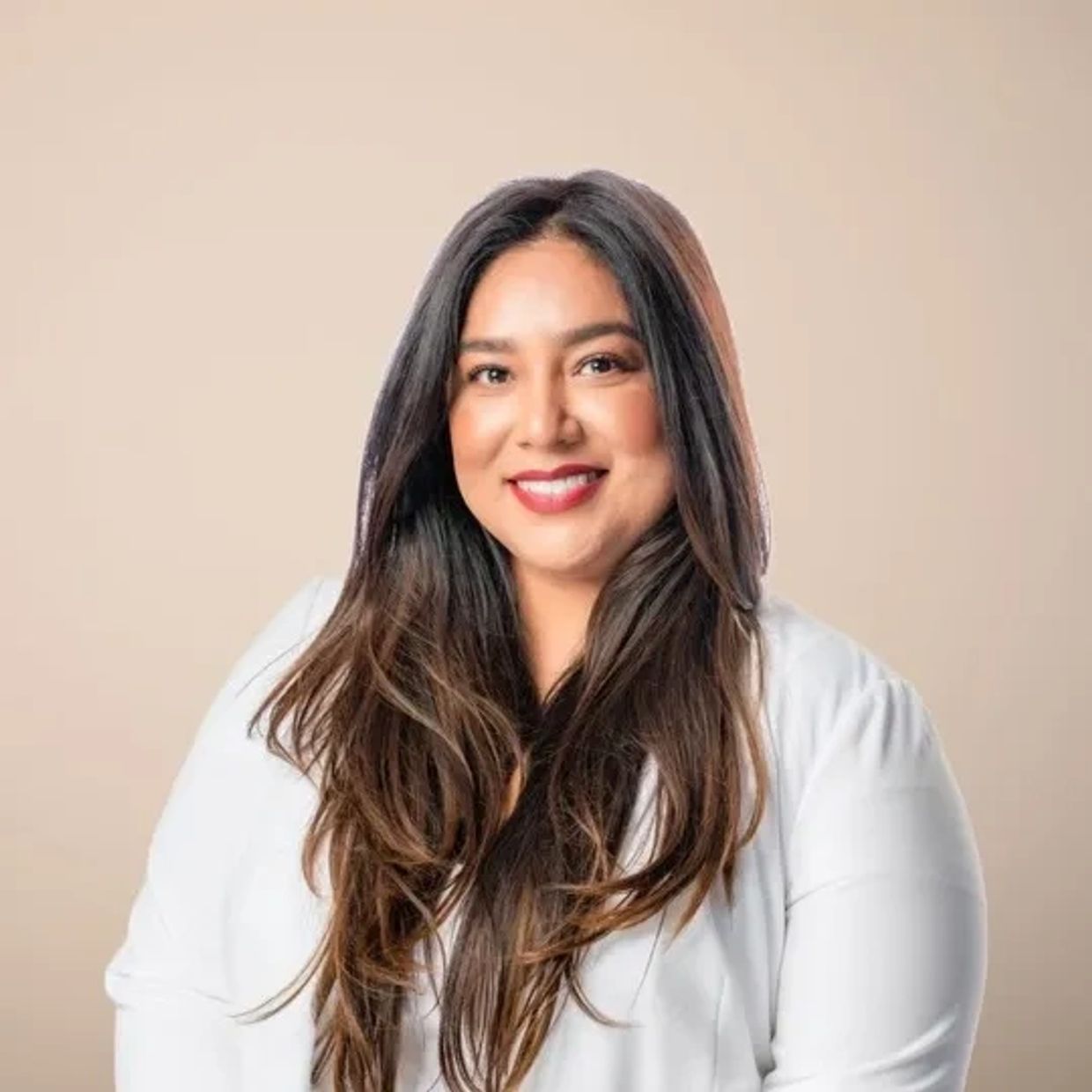 Smiling woman with long dark hair in white blouse.