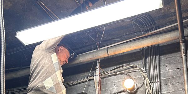 An older man fixing a ceiling light fixture.