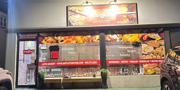 Front view of a Latin bakery with colorful food images and signage.