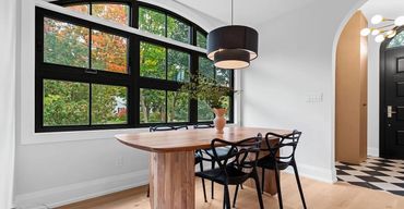 Bright breakfast nook with art deco black-and-white geometric tile floor, large arched black window