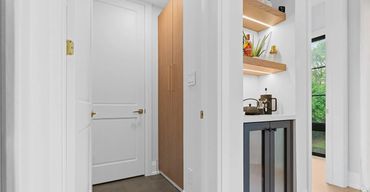 Custom oak cabinetry with two-panel doors, open LED-lit shelves, and bar station in bright space
