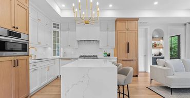 Elegant kitchen with tall oak upper cabinets, white shaker base cabinets, and marble countertops