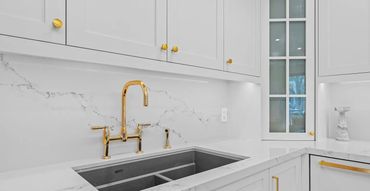 Bright kitchen sink with undermount stainless double bowl, gold bridge faucet, marble countertop