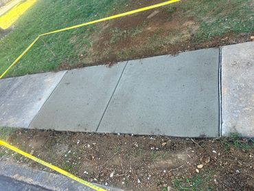 Freshly poured concrete sidewalk sectioned off by caution tape.