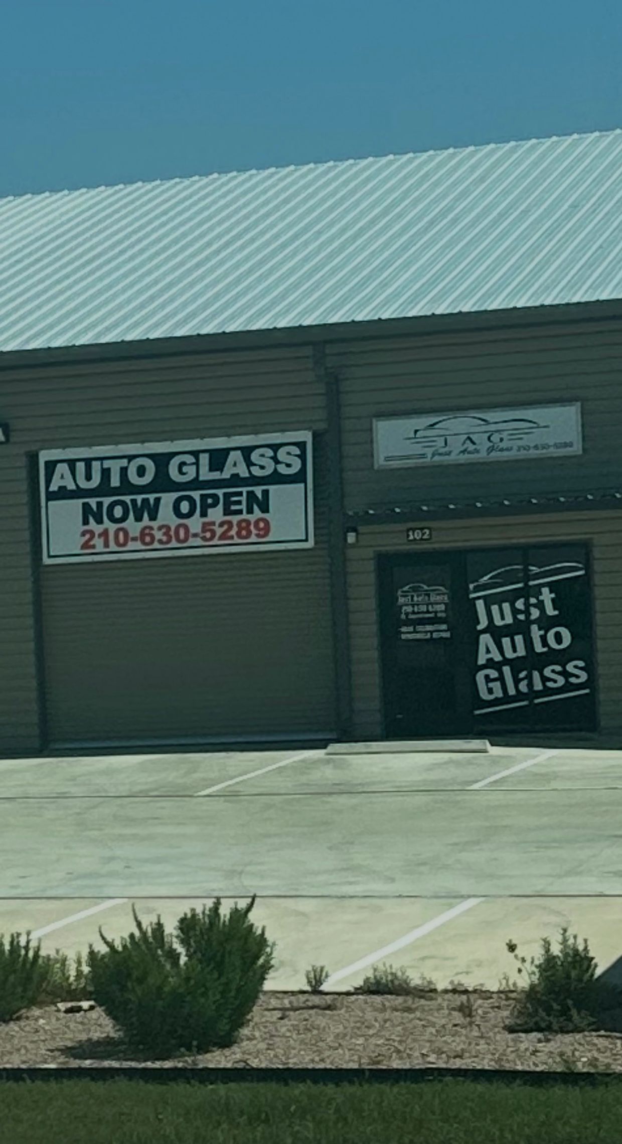 Auto glass shop with 'Now Open' signage and contact number.