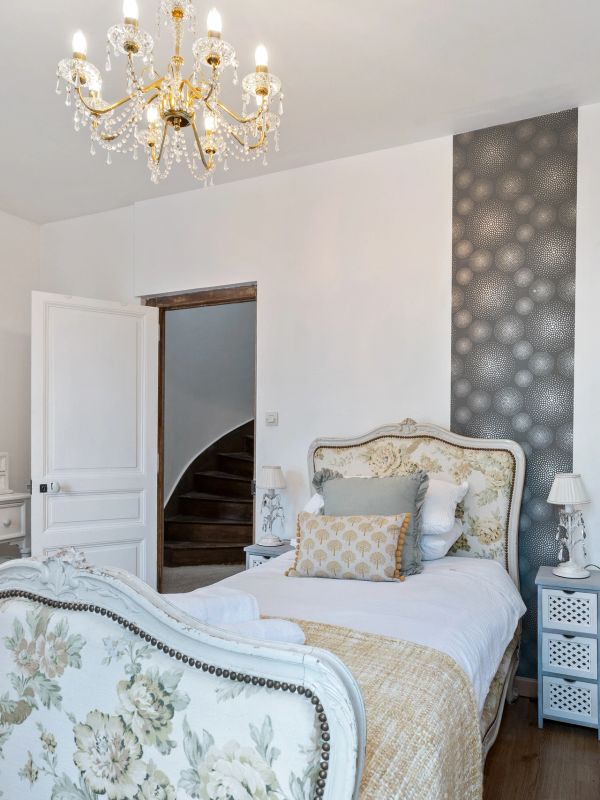 Elegant bedroom with floral decor and chandelier. Light filled. Airbnb.