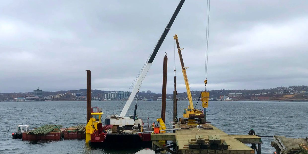 Pile driving from crane barge using vibratory hammer and drop hammer.