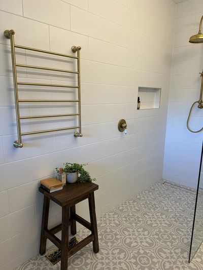 Brushed brass heated towel rail and shower niche in a renovated bathroom