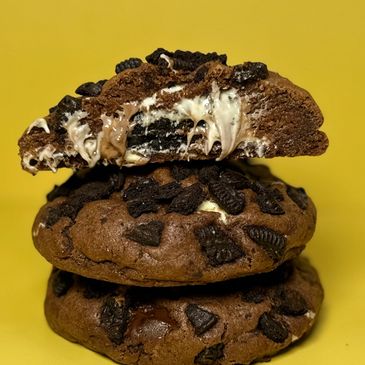 Stack of chocolate cookies with cream-filled Oreo pieces against a yellow background.