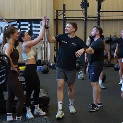 People high-fiving and socializing in a gym setting.