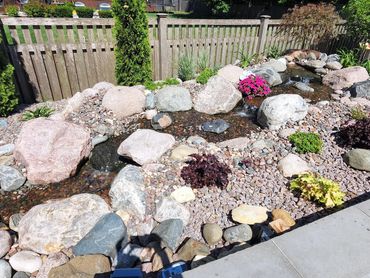 14' pondless waterfall next to your patio creates an inviting spot to sit down and relax.