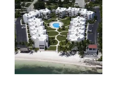 Aerial view of beachfront white residential buildings with pool.
