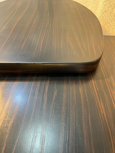 Close-up of a wooden table with a dark finish and natural grain patterns.