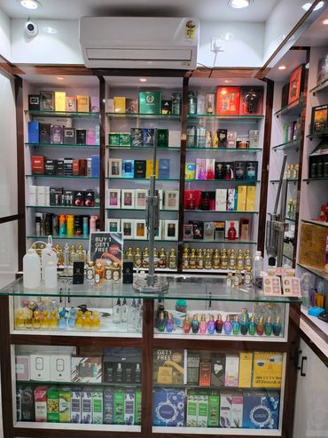 Display of various perfumes and fragrances in a well-lit glass cabinet.