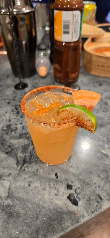 Spicy citrus cocktail with a chili-rimmed glass and lime wedge garnish.